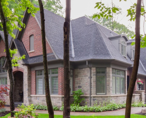 Brick house with stone siding, shingled roof and arched windows.