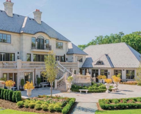 Traditional home with large courtyard, black frame windows and double chimney.