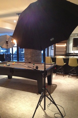 A living room featuring a pool table and a black umbrella, creating a unique and inviting atmosphere.