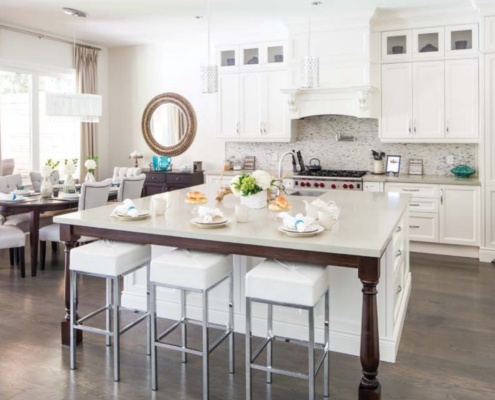 White kitchen with hardwood floor, tile backsplash and large island.