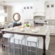 White kitchen with hardwood floor, tile backsplash and large island.