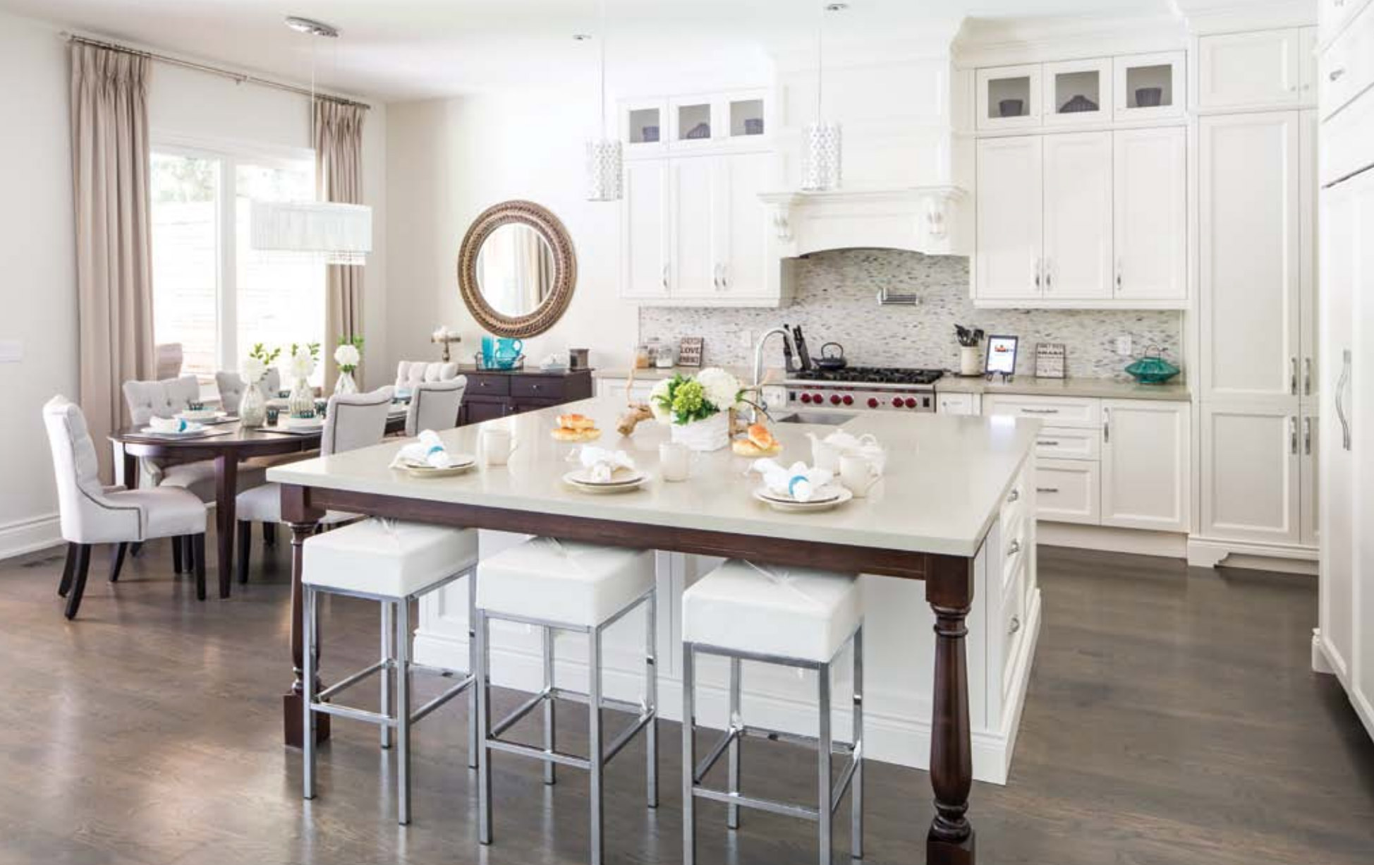 White kitchen with hardwood floor, tile backsplash and large island.