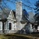 Traditional house with blue siding, stone chimney, and stone skirt.