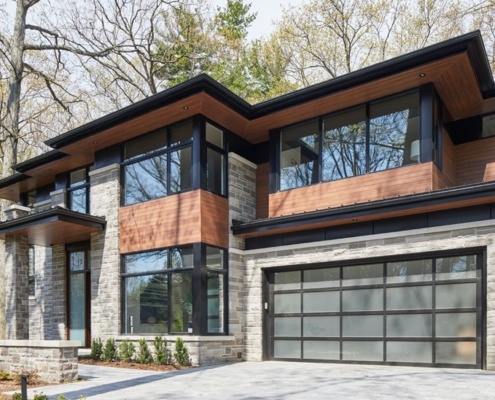 Natural modern home with corner windows, frosted glass garage door and landscape wall.