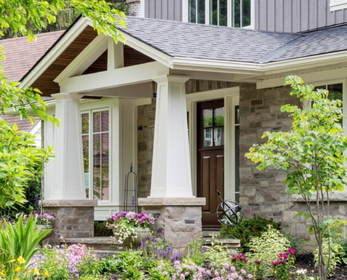 Traditional renovation with gray wood siding, white eaves and white columns.