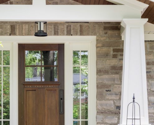 Traditional home with wood front door, stone siding and white trim.