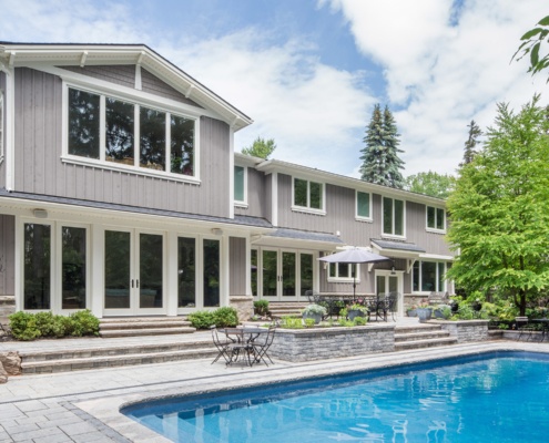 Home backyard with inground pool, floor to ceiling windows and stone chimney.