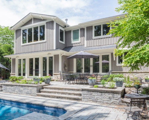 Home exterior with wood siding, stone porch and white trim.