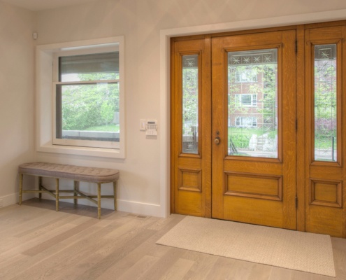 Home foyer with wood front door, white frame window and white trim.