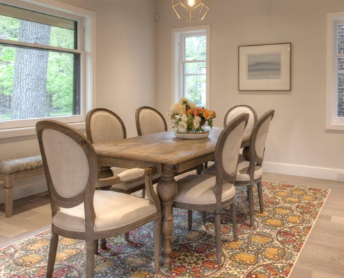 Dining room with hardwood floor, wood dining table and white frame window.