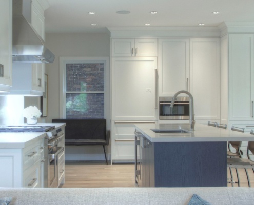 White kitchen with breakfast bar, gray countertops and white frame windows.
