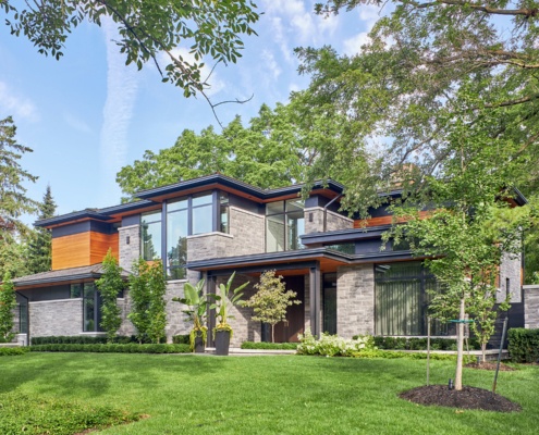 Exterior of modern house with shingled roof, floor to ceiling window and clean lines.