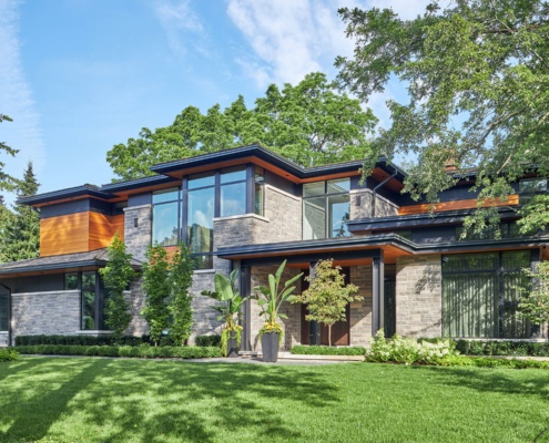 Natural modern house with wood siding, flat roof black windows.