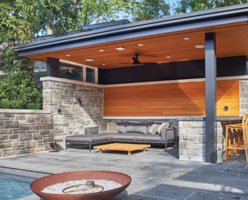 Flagstone deck with covered patio, wood soffit and stone wall.