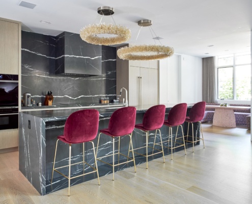 Modern kitchen with marble backsplash, wood cabinets, and breakfast bar.
