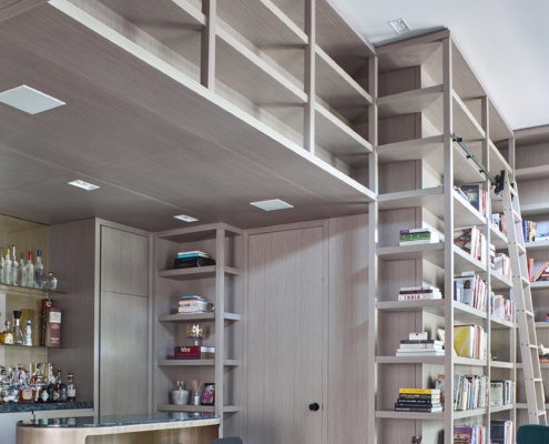 Modern home bar with wood trim, built in shelves and hardwood floor.