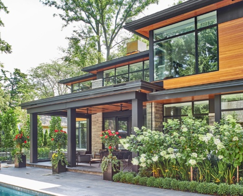 Modern house with flagstone patio, wood siding and dark trim.