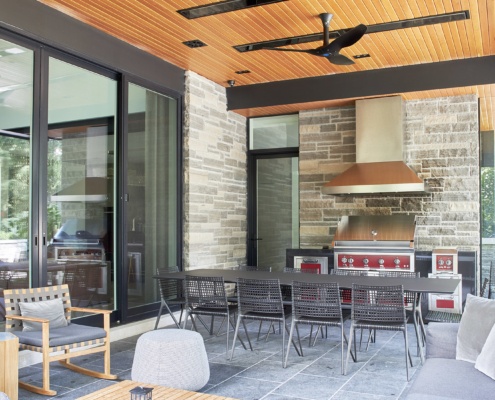 Modern home with outdoor kitchen, covered patio and wood ceiling.