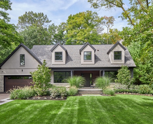 Traditional house with gabled roof, stucco siding and black trim.