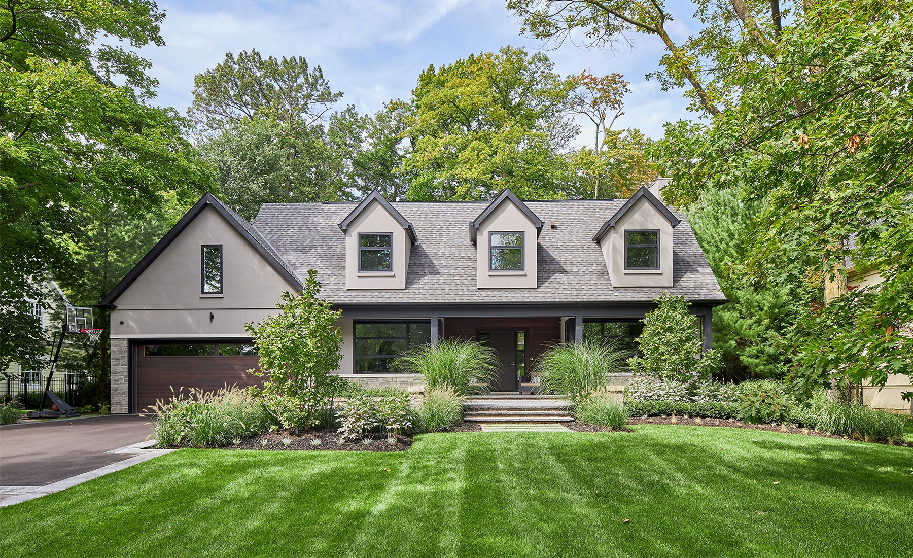 Traditional house with gabled roof, stucco siding and black trim.