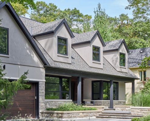 Transitional home with wood garage door, stucco siding and stone planter.