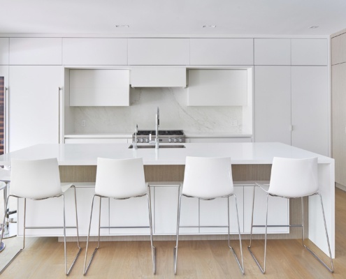 Contemporary kitchen with black frame window, white pot lights and marble backsplash.