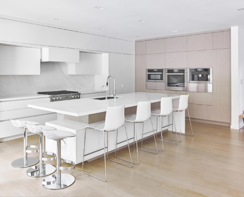 Kitchen with marble backsplash, white island and white cabinetry.