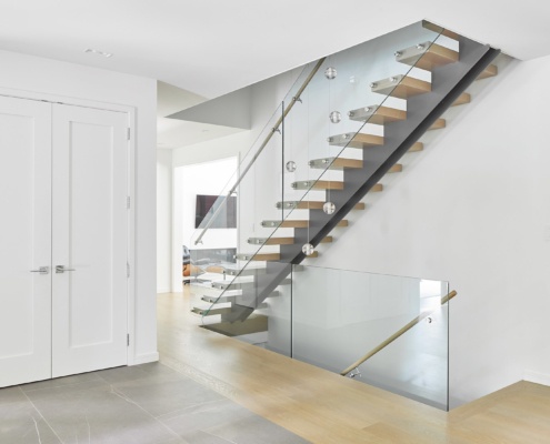 Floating staircase with glass railing, wood treads and tile floor.