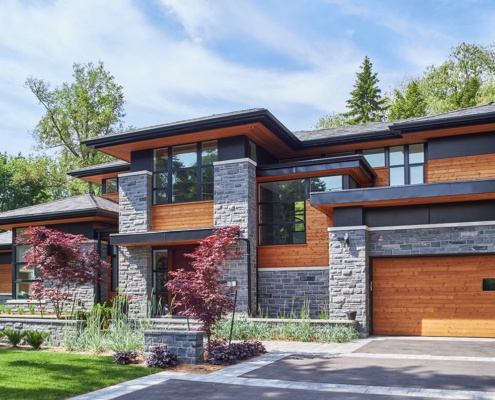 Natural modern house with wood garage door, wood soffit and natural stone siding.