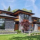 Modern house with floating roof, stone landscape wall and wood siding.