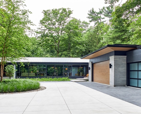 Modern house with circular driveway, wood soffit and stone siding.