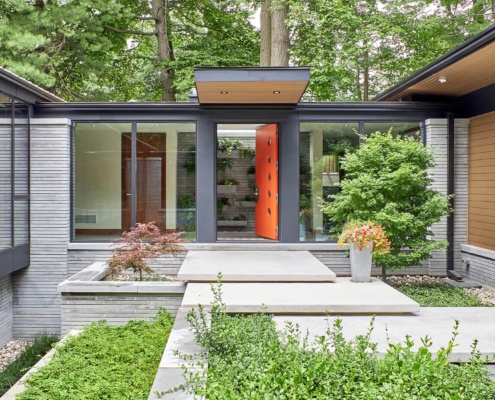 Front elevation with open front door, concrete steps and stone planter.