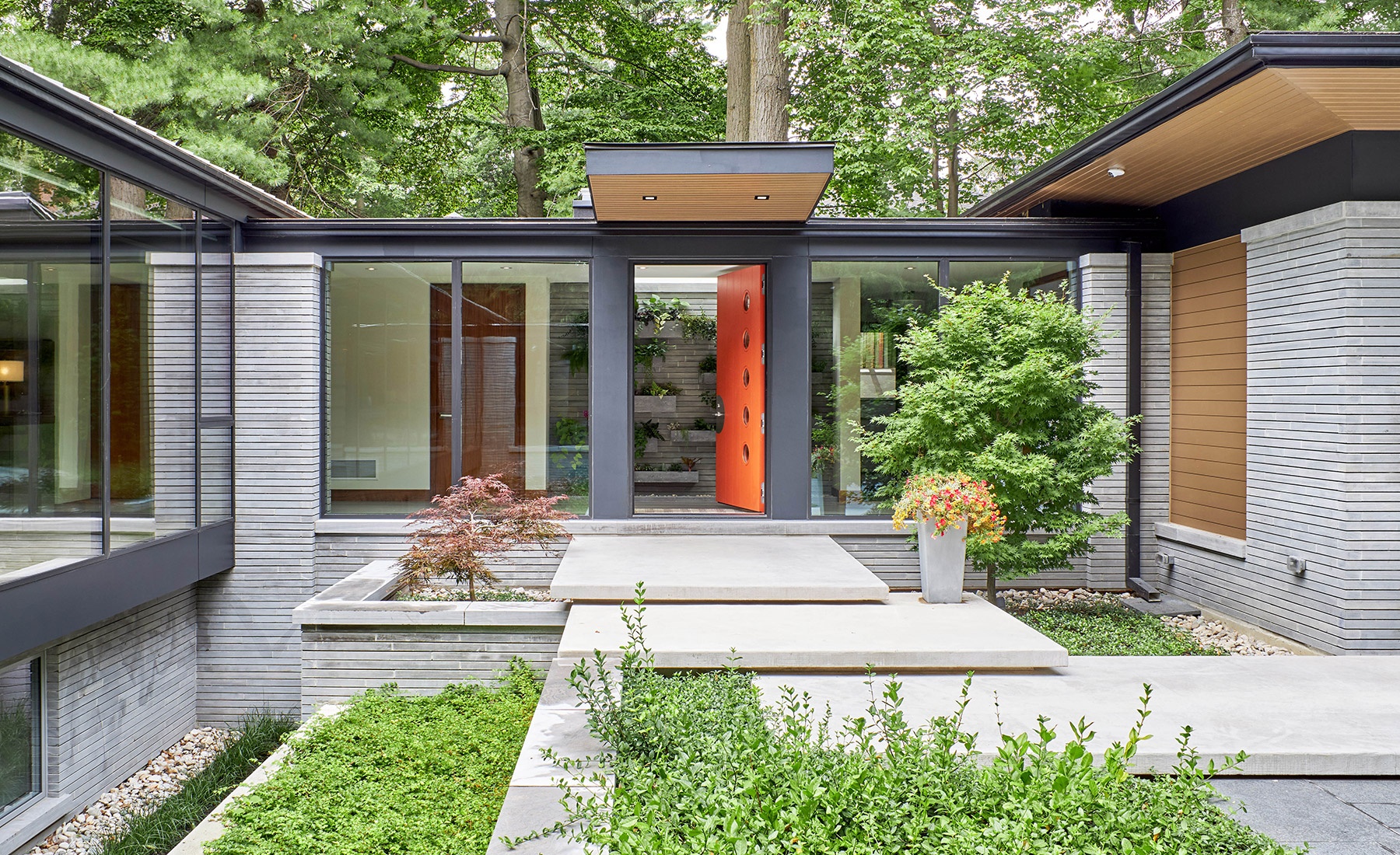 Front elevation with open front door, concrete steps and stone planter.