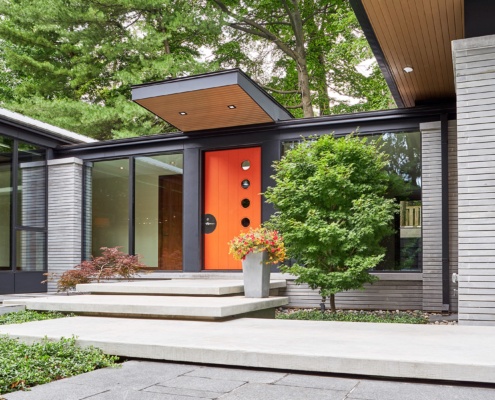 Covered entry with floor to ceiling window and stone siding.