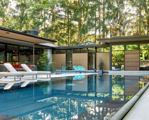 Modern home with inground lap pool, floor to ceiling windows and metal siding.
