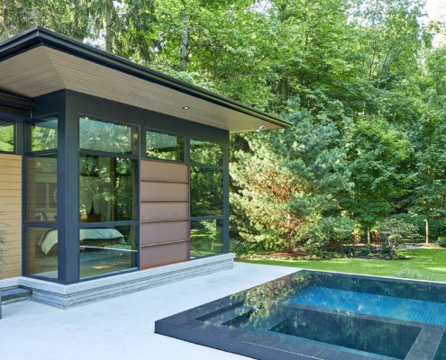 Bungalow with lap pool, metal siding and black trim.