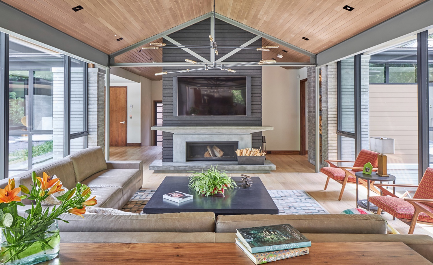 Modern family room with brick fireplace, stone wall and wood ceiling.