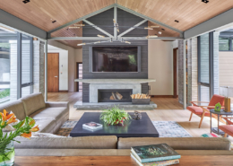 Modern family room with brick fireplace, stone wall and wood ceiling.