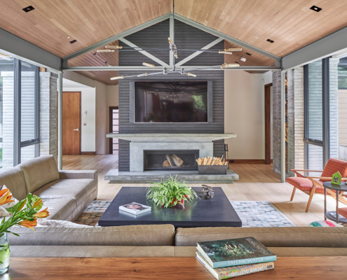 Modern family room with brick fireplace, stone wall and wood ceiling.