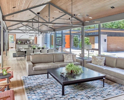 Contemporary living area with hardwood floor, modern chandelier and large window.