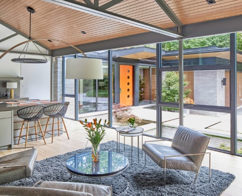 Modern sitting area with wood ceiling, black frame window, large island.