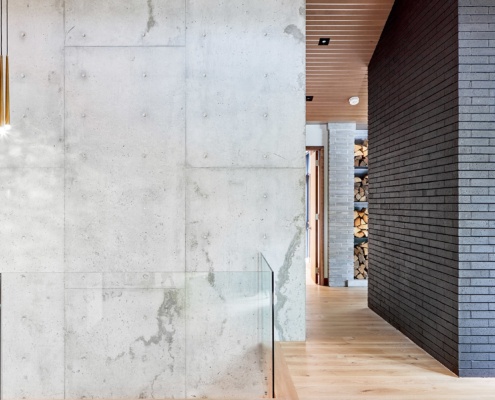 Staircase with modern chandelier, brick wall and concrete wall.