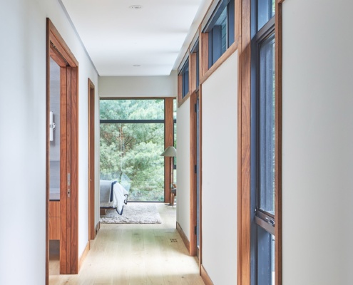 Hallway with wood trim, floor to ceiling window and black frame window.