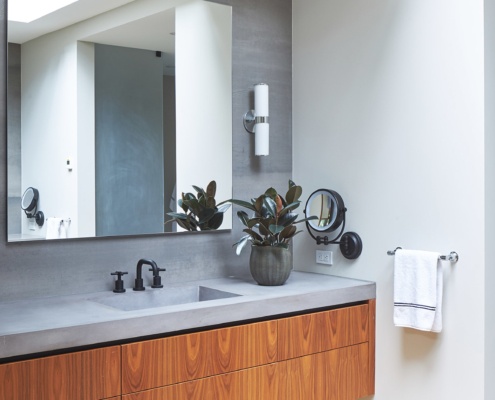 Bathroom with floating vanity, concrete backsplash and wood baseboard.