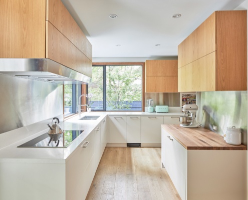 Modern kitchen with corner window, wood cabinets and hardwood floor.