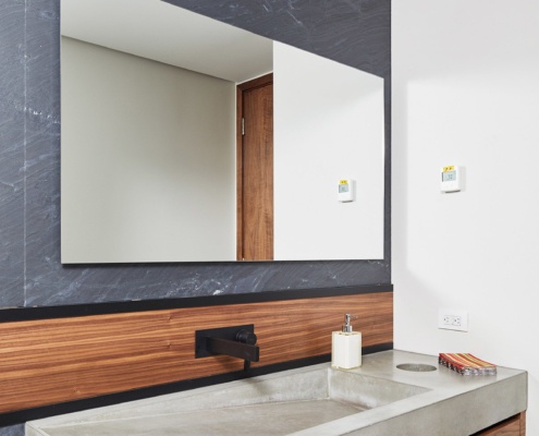 Powder room with floating vanity, stone wall and custom sink.