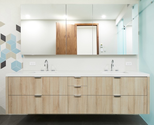 Modern bathroom with double sinks, floating vanity and tile wall.