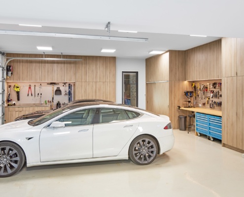 Modern garage with wood cabinetry, concrete floor and high ceiling.