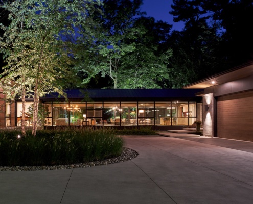 Modern house with steel cladding, horizontal stone, and floor to ceiling window.