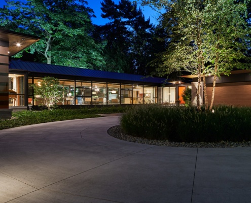 Mid century modern house with gabled roof, large windows and wood soffit.